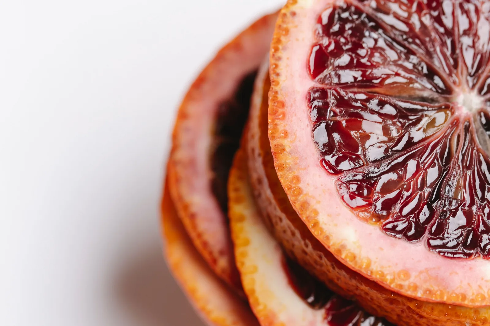 Aufgeschnittene Blutorange mit tiefrotem Fruchtfleisch neben ätherischem Öl in einer kleinen Glasflasche
