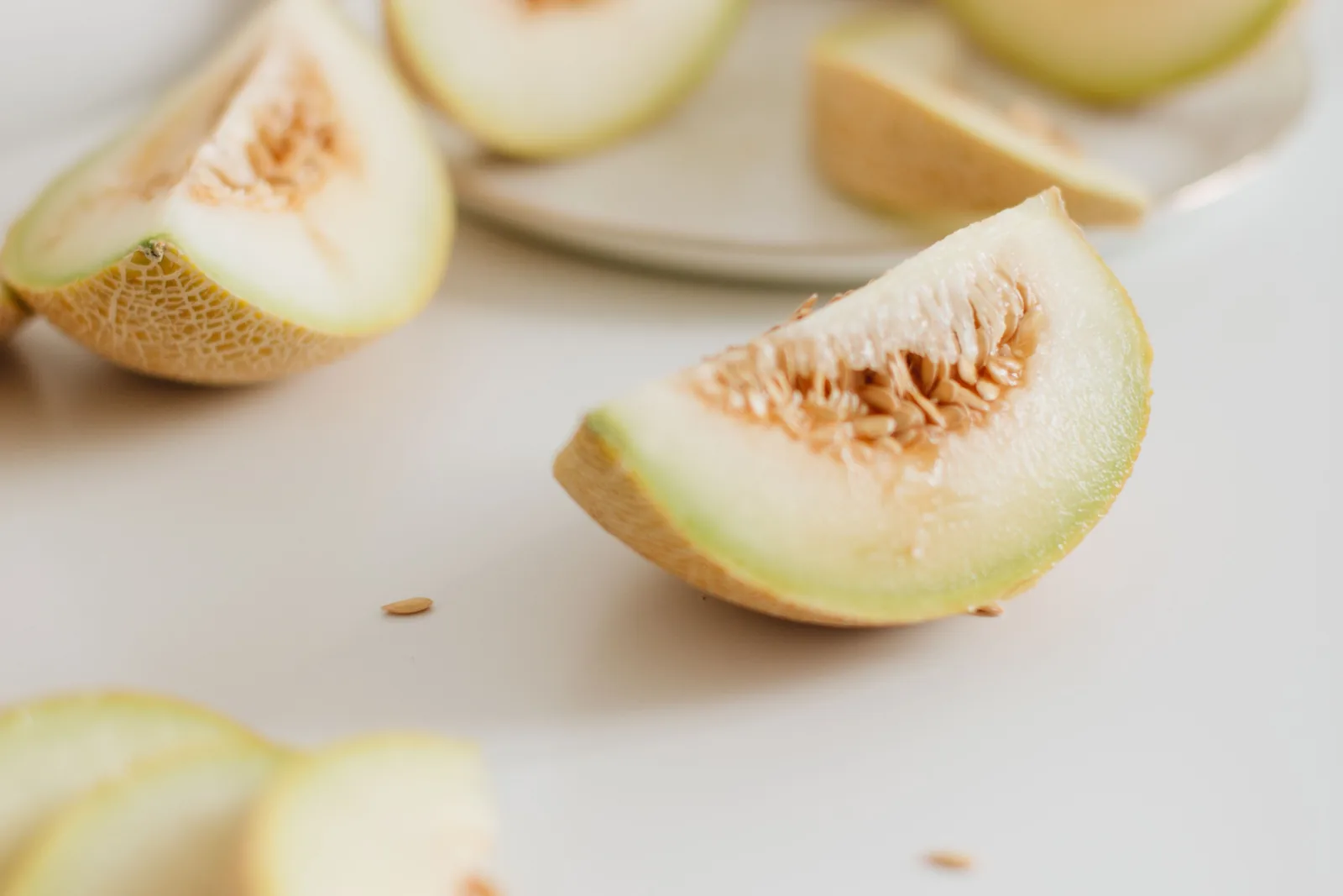Aufgeschnittene Honigmelone mit Wassertropfen, daneben ein Parfümflakon im warmen Sommerlicht