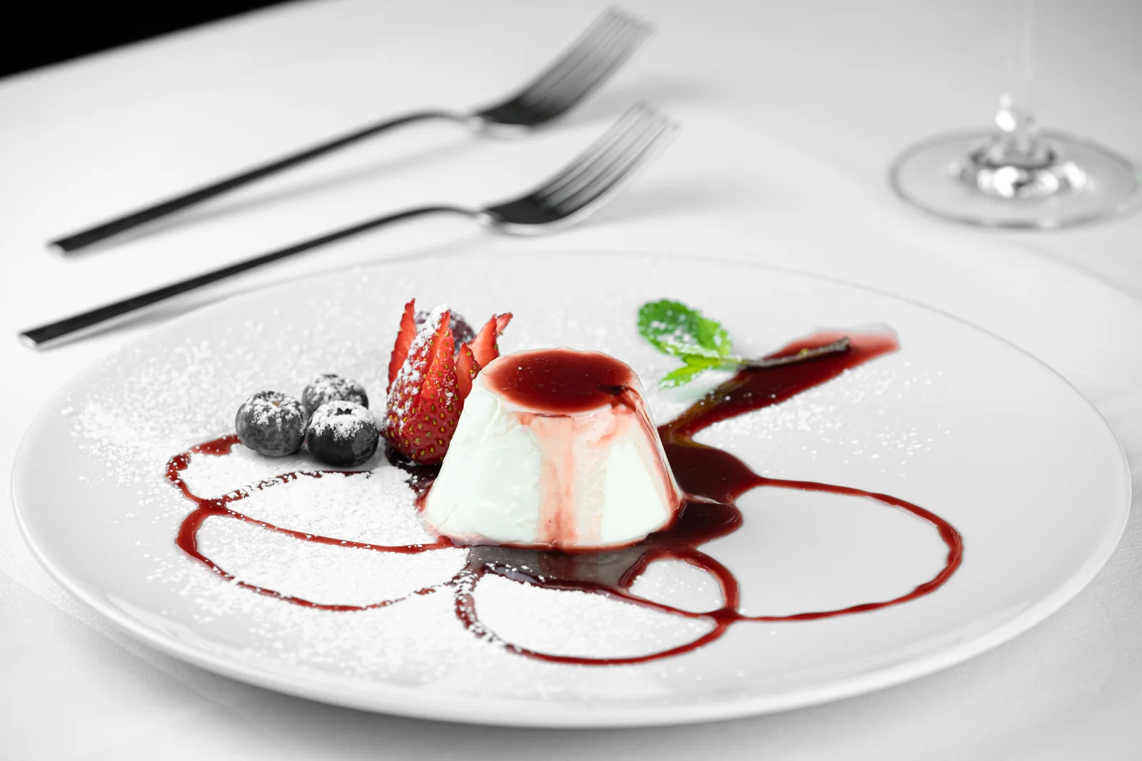 Panna Cotta in einer Glasschale mit Karamellsauce, daneben eine Vanilleschote als Sinnbild für die cremig-süße Duftnote