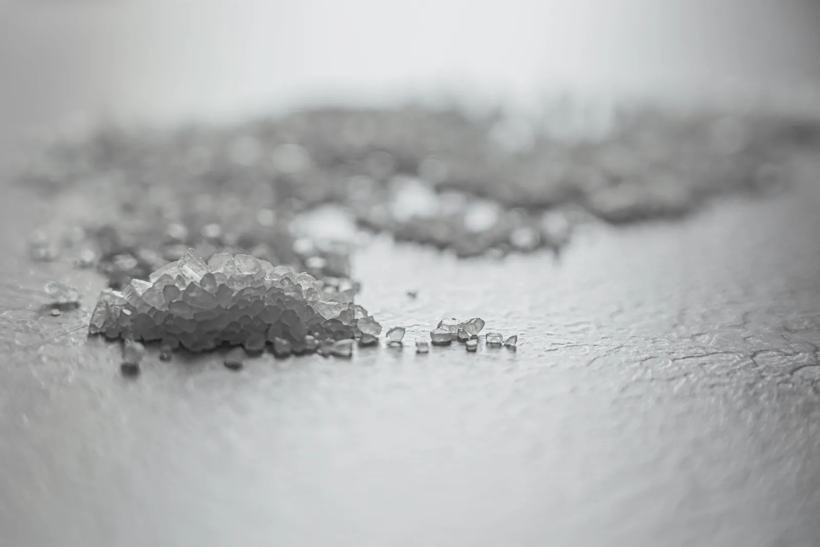 Grobes Meersalz auf dunklem Stein, im Hintergrund verschwommene Wellen an einem Strand