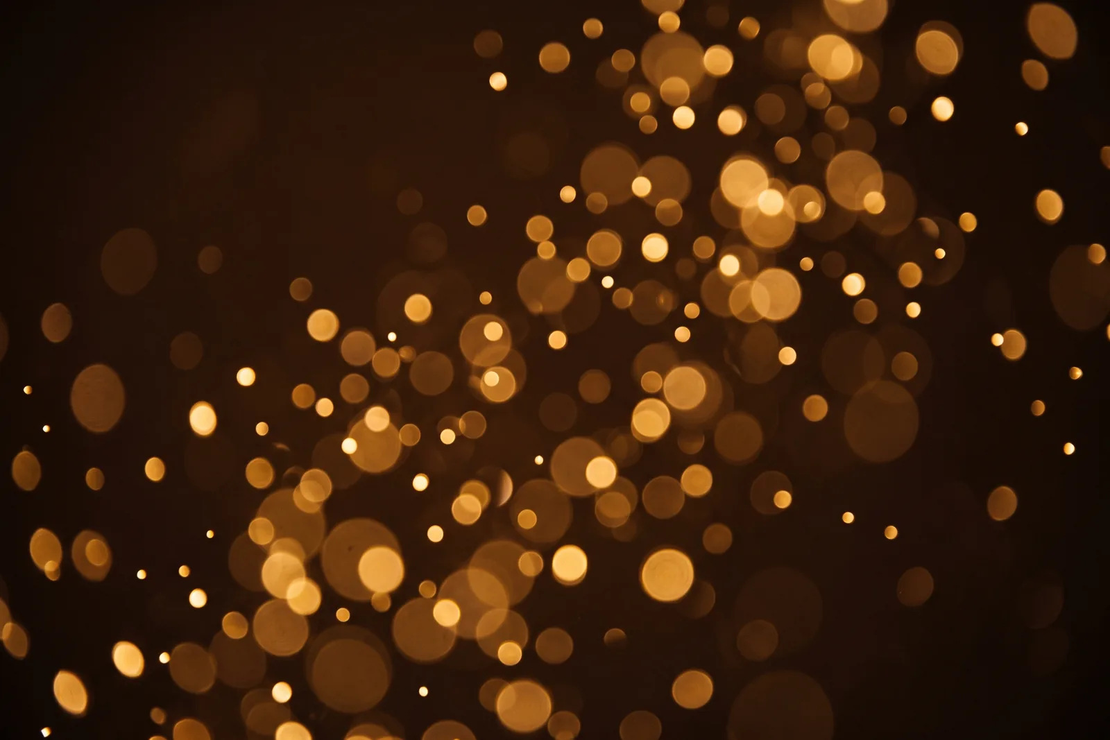 Warme goldene Lichtpunkte vor dunklem Hintergrund als Sinnbild für einen besonderen, ungewöhnlichen Duftcharakter